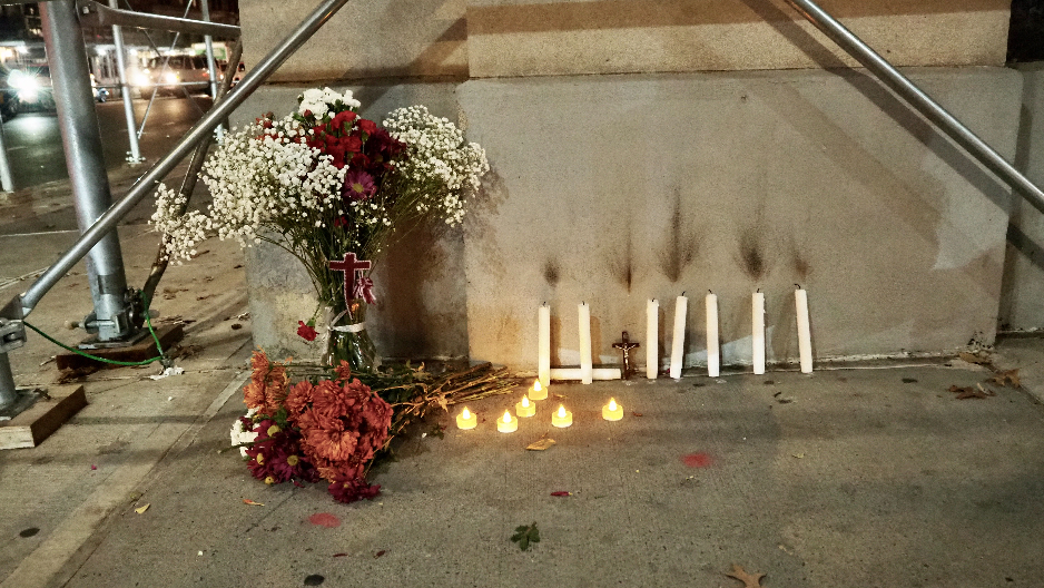 Candles and flowers are left under scaffolding as a makeshift vigil for an unknown construction worker who died on November 29, 2022.